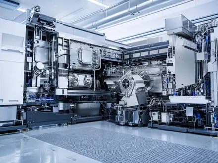 ASML Holding NL0010273215 fotorealistische EUV Lithographiemaschine steht im modernen Halbleiter Reinraum beleuchtet - Foto: THN