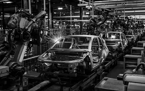 Tesla US88160R1014 Schwarz Weiss Reportage zeigt Roboterarm schweißt Elektroauto Karosserie in Fabrik - Foto: THN