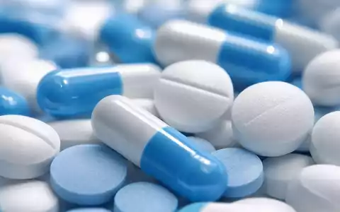 AstraZeneca US6549022043 Makroaufnahme generischer blauer und weißer Tabletten sowie Kapseln ohne Markierungen - Foto: THN