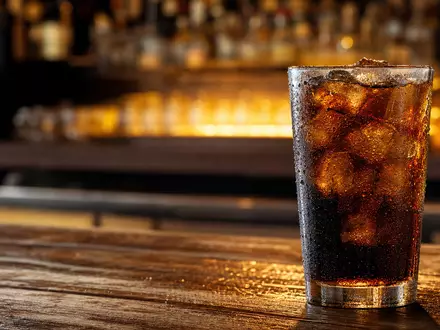 PepsiCo US7134481081 zeigt ein eisgekühltes Cola-Getränk in einem generischen Glas auf dunkler Holztheke - Foto: THN