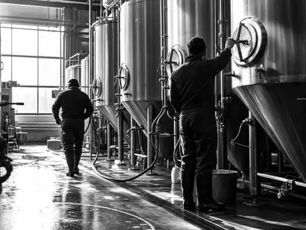 Schwarzweiß-Reportage zeigt Brauereiarbeiter an Gärtanks, dokumentiert Produktion bei Anheuser-Busch InBev, ISIN BE0974293251, weltgrößter Brauerei-Konzern - Foto: THN