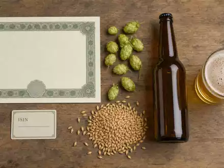 Flatlay mit Aktienzertifikat, ISIN-Karte und Hopfen zeigt die Aktie Anheuser-Busch InBev, ISIN BE0974293251 - Foto: THN