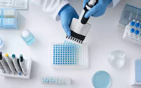 Argenx NL0010832176 Mehrkanal-Pipette befüllt von oben eine blaue 96-Well-Platte im Immunologie-Labor sorgfältig - Foto: THN