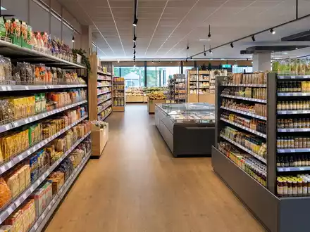 Ahold NL0011794037 fotorealistischer Blick in einen hellen europäisch niederländischen Supermarkt Innenraum mit vollbestückten Regalen - Foto: THN