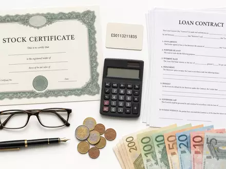 Flatlay mit Aktienzertifikat, ISIN-Karte und Finanzutensilien illustriert Investment in BBVA (Banco Bilbao) ISIN ES0113211835 - Foto: THN
