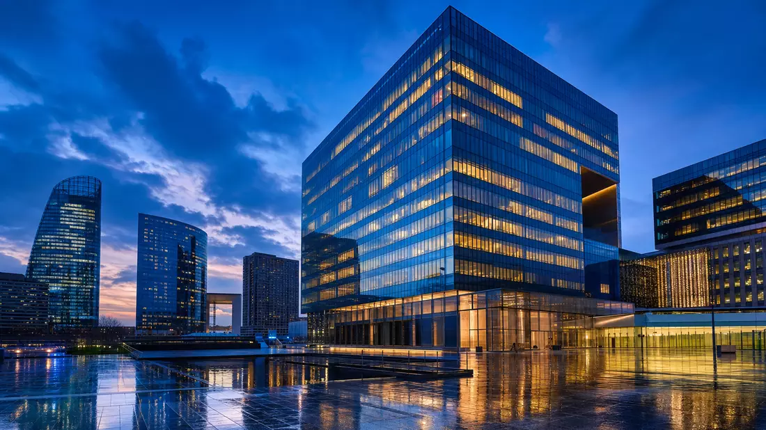Modernes Bürohochhaus in Paris La Défense zur blauen Stunde mit Reflexionen im Pflaster