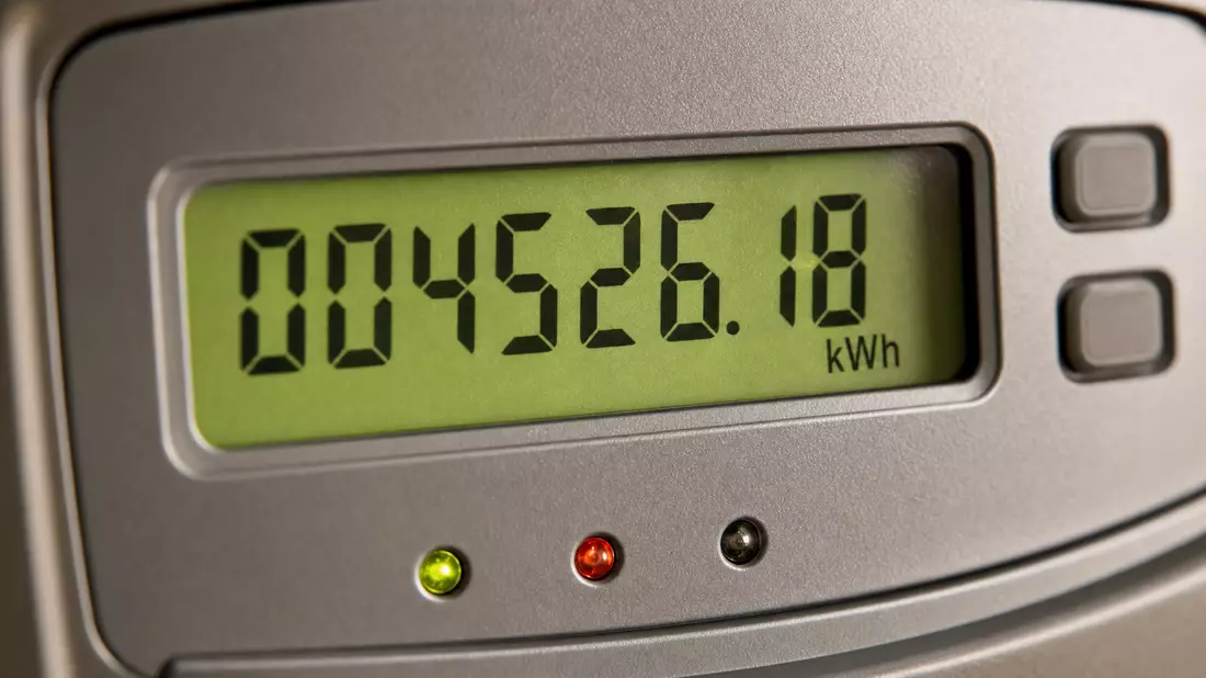 Extreme macro close-up of digital electricity meter LCD display showing kilowatt-hour consumption figures