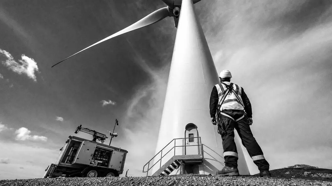 Schwarz-Weiß-Reportage: Wartungstechniker mit Schutzausrüstung an Windturbinen-Basis, EDP Renováveis