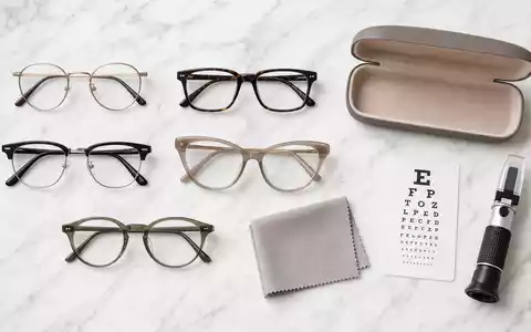 EssilorLuxottica FR0000033219 flatlay of eyeglass frames, leather case, cleaning cloth, and refractometer on marble - Foto: THN