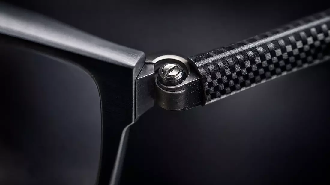 Extreme macro photo of an eyeglass frame hinge with precision screw and carbon fiber texture temple arm