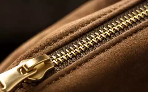 Kering FR0000121964 macro detail gold zipper on dark suede leather luxury craftsmanship shallow depth - Foto: THN