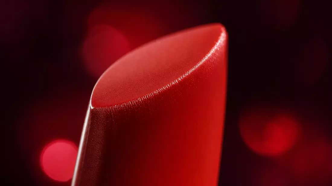 Extreme macro close-up of a red lipstick tip showing creamy texture and specular light reflection