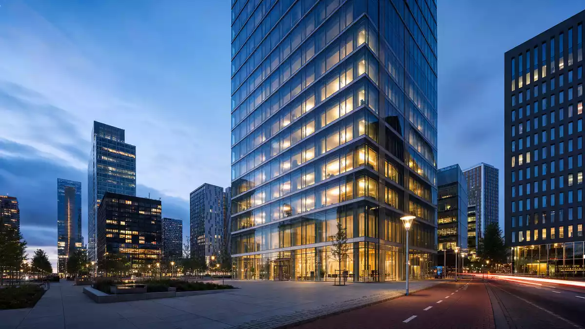 Modernes Glas-Bankhochhaus im Amsterdamer Finanzdistrikt Zuidas bei Abenddämmerung