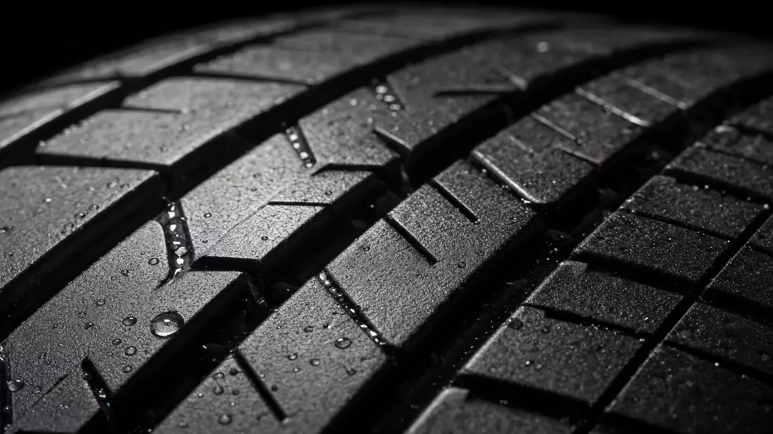 Extreme macro photograph of car tire tread surface showing deep grooves and rubber texture detail