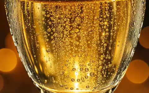 LVMH FR0000121014 Makrofoto goldener Champagnerblasen im Kristallglas mit Bokeh Lichtreflexen und Kondensation - Foto: THN