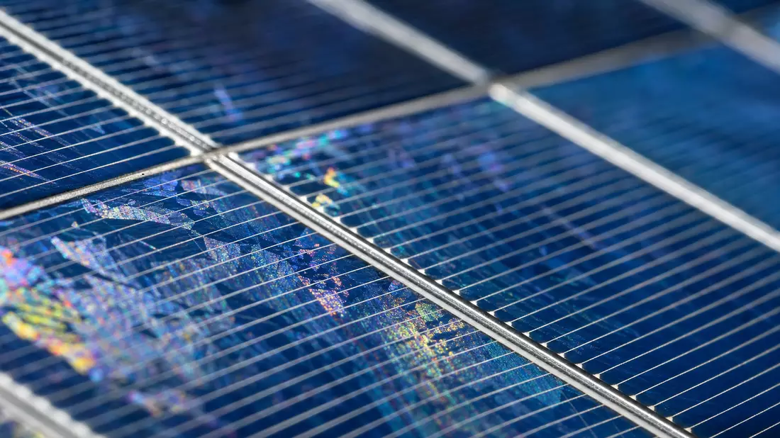 Extreme macro of photovoltaic solar cell showing crystalline silicon wafer and iridescent busbar grid