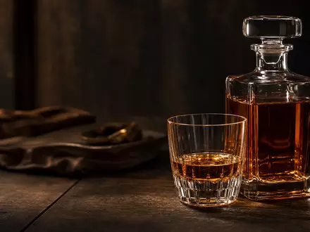 Pernod Ricard FR0000120693 — amber spirits decanter with crystal tumbler on dark oak - Foto: THN