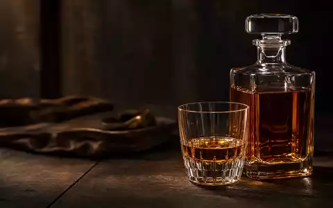 Pernod Ricard FR0000120693 — amber spirits decanter with crystal tumbler on dark oak - Foto: THN
