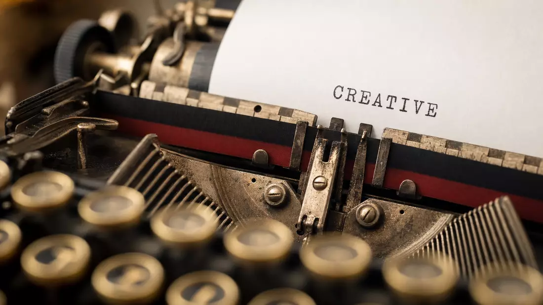 Extreme macro close-up of a vintage typewriter with the word CREATIVE typed on white paper