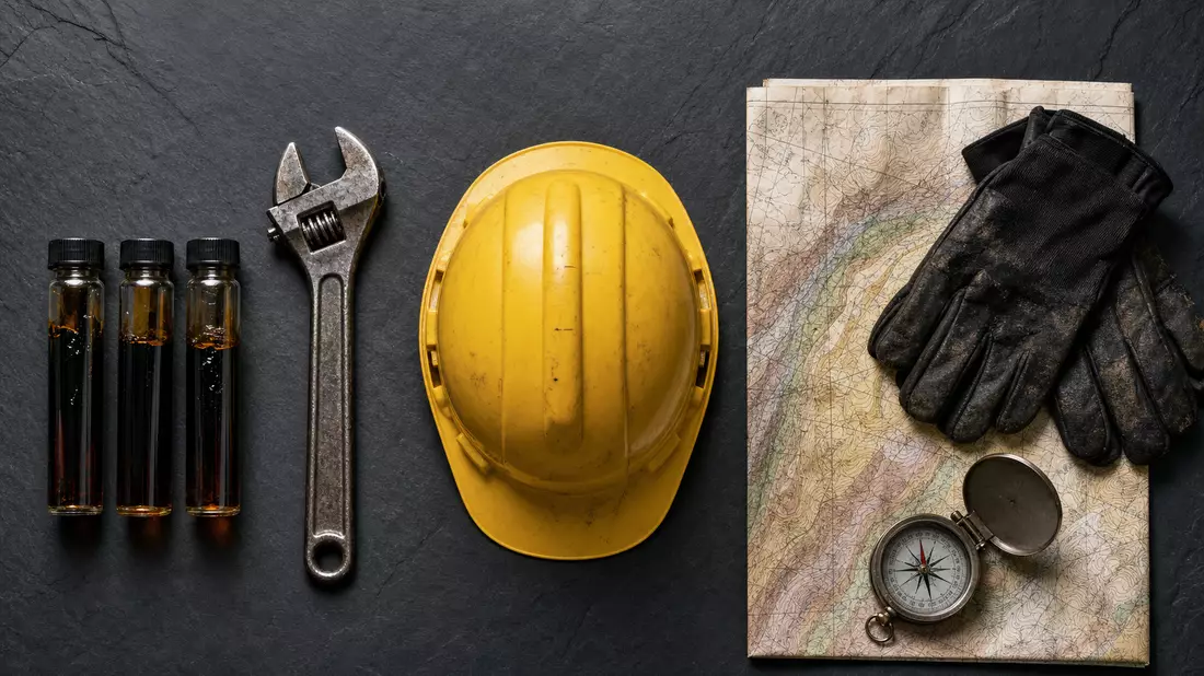 Flatlay von Erdöl-Probefläschchen, Werkzeug, Helm, Geo-Karte und Handschuhen