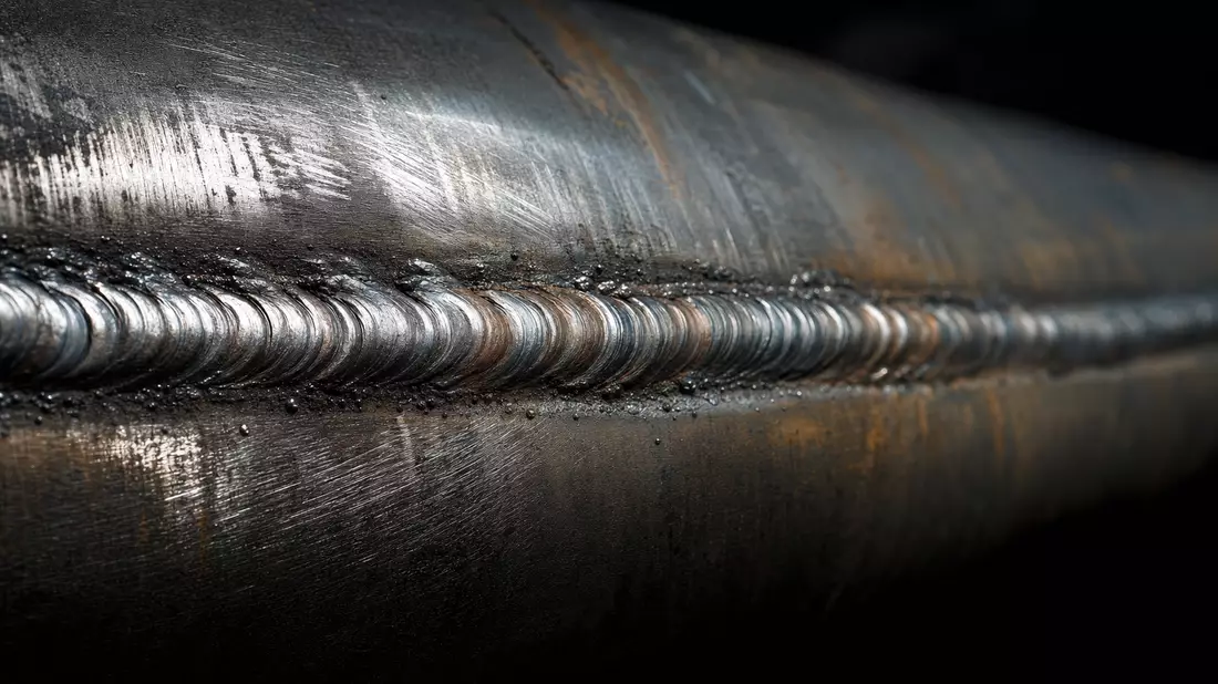 Makro-Detailaufnahme einer Pipeline-Schweißnaht mit Stahltextur und Lichtreflex