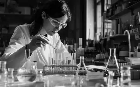 Sanofi FR0000120578 black-and-white reportage scientist wearing goggles using pipette in pharmaceutical research laboratory - Foto: THN