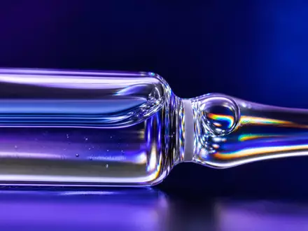 Sanofi FR0000120578 extreme macro detail of sealed glass pharmaceutical ampoule with prismatic light reflections - Foto: THN