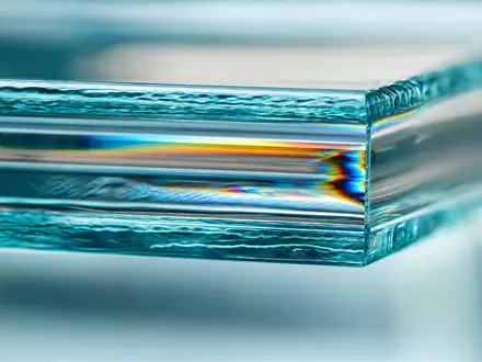 Saint-Gobain FR0000125007 Makroaufnahme einer Glaskante mit prismatischen Brechreflexen Regenbogenlicht und sichtbarem Schichtaufbau - Foto: THN