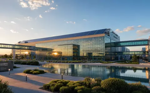 STMicroelectronics NL0000226223 modern semiconductor fab with solar roof and glass bridges at golden hour - Foto: THN