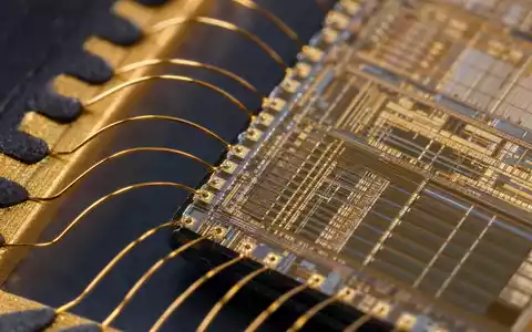 STMicroelectronics NL0000226223 extreme macro close-up microchip die with golden bond wire connections visible - Foto: THN