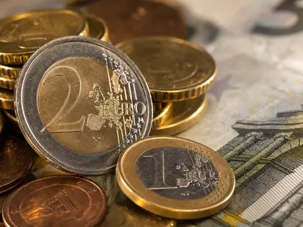 Intesa Sanpaolo IT0000072618 – Makro-Aufnahme von gestapelten Euro-Münzen und Banknoten mit warmem Bokeh-Hintergrund - Foto: THN