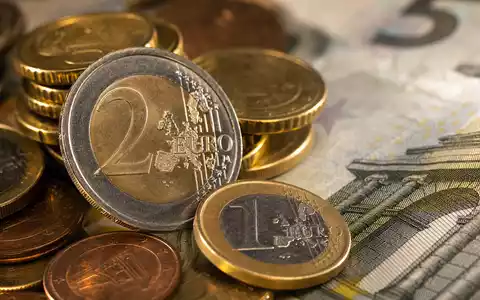 Intesa Sanpaolo IT0000072618 – Makro-Aufnahme von gestapelten Euro-Münzen und Banknoten mit warmem Bokeh-Hintergrund - Foto: THN