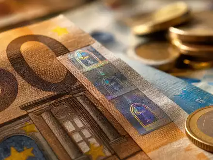 UniCredit IT0005239360 – Makro-Nahaufnahme von Euro-Banknoten mit schimmerndem Sicherheitsstreifen und unscharfen Münzstapeln im Hintergrund - Foto: THN
