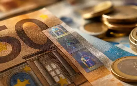 UniCredit IT0005239360 – Makro-Nahaufnahme von Euro-Banknoten mit schimmerndem Sicherheitsstreifen und unscharfen Münzstapeln im Hintergrund - Foto: THN