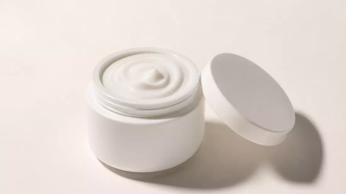 Geöffnete weiße Cremedose mit glatter Creme-Textur auf hellem Studio-Hintergrund