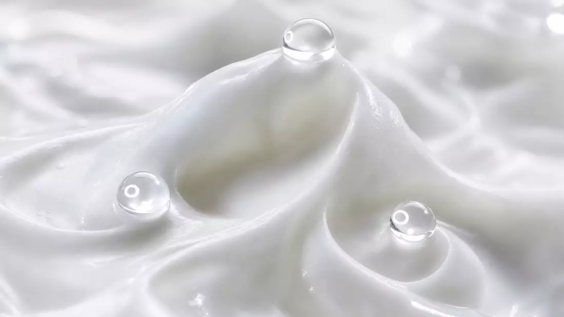 Extreme Makroaufnahme von weißer Creme-Textur mit drei Wassertropfen