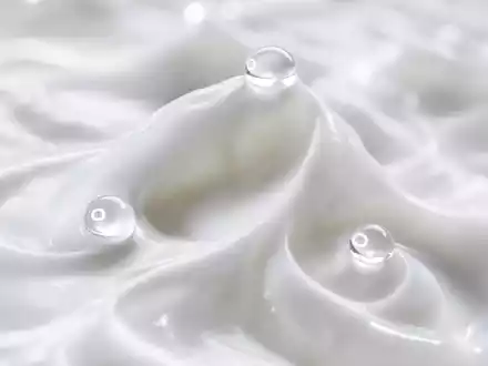 Extreme Makroaufnahme weißer Cremtextur mit Wellen und Spitzen; drei kristallklare Wassertropfen fangen das Licht. Flacher Schärfebereich, perlige Weißtöne, kein Verpackungsmaterial sichtbar - Foto: THN