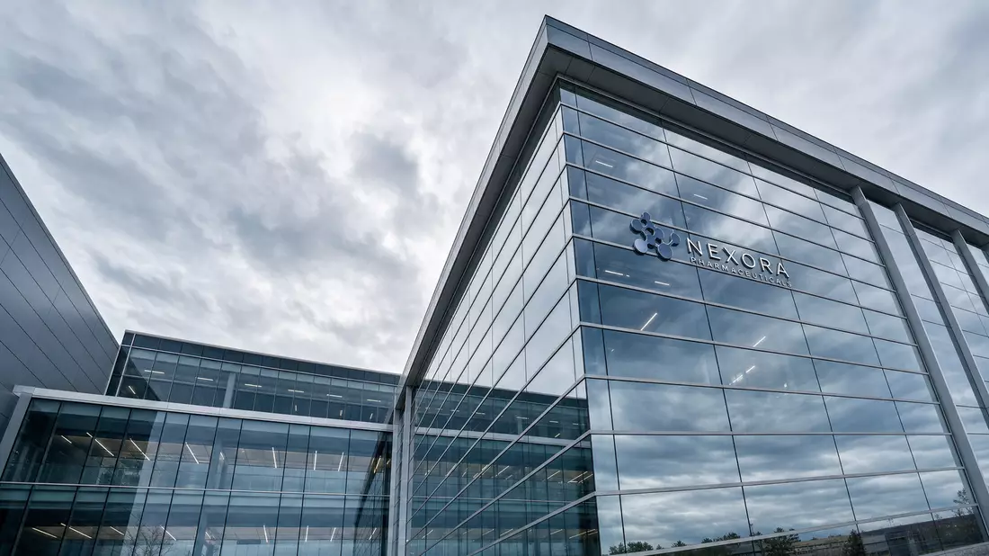 Architekturfotografie: modernes Pharma-Forschungsgebäude mit Vorhangfassade aus Stahl und Glas, aufgenommen von unten mit starker perspektivischer Linienführung bei bedecktem Himmel