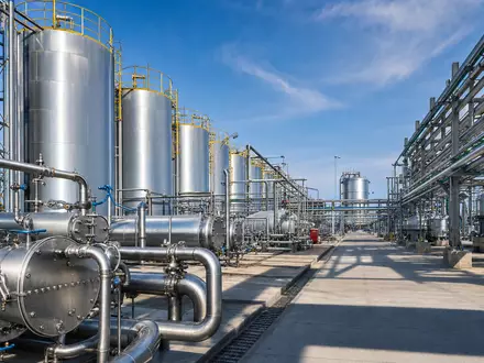 Fotorealistisches Chemie-Tanklager mit Edelstahltanks und Rohrleitungen bei Tageslicht – repräsentativ für Brenntag SE (ISIN DE000A1DAHH0) als globalen Chemiedistributor - Foto: THN