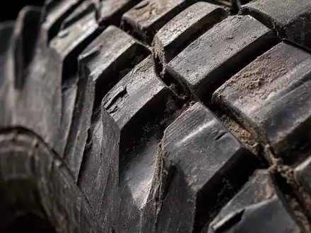 Extreme Nahaufnahme eines schweren LKW-Reifenprofils mit Schmutzablagerungen in den Rillen – verdeutlicht die technische Robustheit und Belastbarkeit der Nutzfahrzeuge der Daimler Truck Holding AG (ISIN DE000DTR0CK8) - Foto: THN