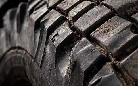 Extreme Nahaufnahme eines schweren LKW-Reifenprofils mit Schmutzablagerungen in den Rillen – verdeutlicht die technische Robustheit und Belastbarkeit der Nutzfahrzeuge der Daimler Truck Holding AG (ISIN DE000DTR0CK8) - Foto: THN