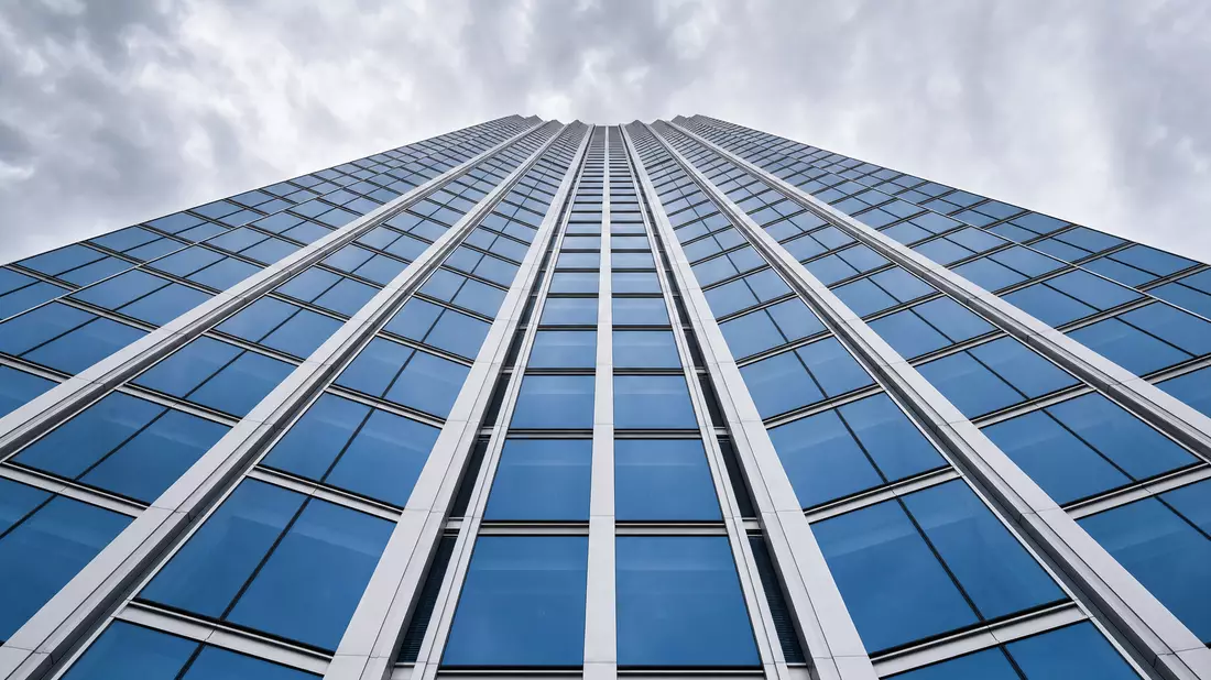 Blick von unten auf Glas-Stahl-Hochhaus mit symmetrischer Fassadenstruktur