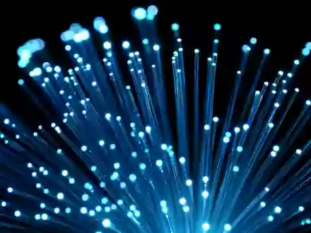 Extreme Makroaufnahme eines leuchtenden Glasfaserbündels mit intensiven Lichtsignalen – visualisiert die Hochgeschwindigkeits-Glasfaserinfrastruktur der Deutsche Telekom AG (ISIN DE0005557508) - Foto: THN