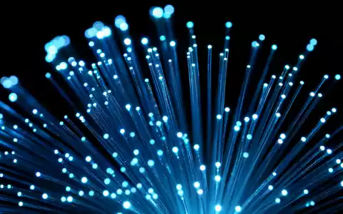 Extreme Makroaufnahme eines leuchtenden Glasfaserbündels mit intensiven Lichtsignalen – visualisiert die Hochgeschwindigkeits-Glasfaserinfrastruktur der Deutsche Telekom AG (ISIN DE0005557508) - Foto: THN
