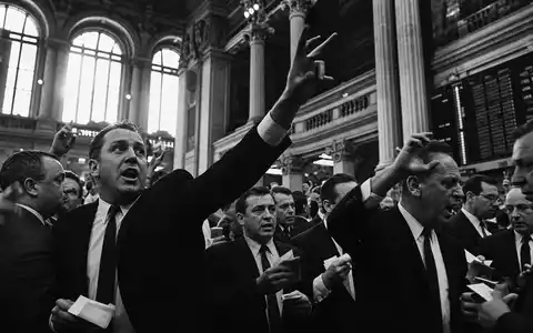 Klassische Schwarzweiß-Reportagefotografie im Stil der Deutsche Börse AG (ISIN DE0005810055): Parketthändler im historischen Frankfurter Börsensaal mit dramatischer Gestikulation und Chiaroscuro-Licht - Foto: THN