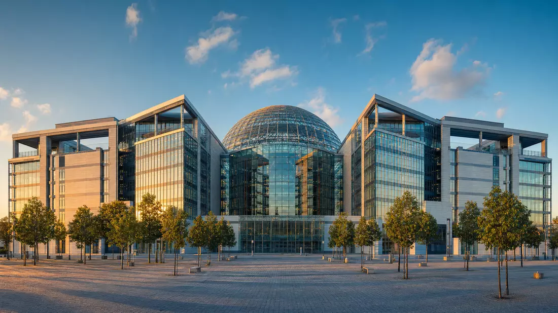Modernes Börsengebäude mit Glaskuppel und Baumreihen bei Abendlicht
