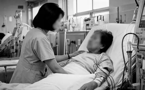 Eine eindringliche Schwarzweiß-Reportageaufnahme einer Pflegekraft beim Betreuen eines Patienten an einer Dialysemaschine – ein Motiv, das die menschliche Dimension der Dialyseversorgung wie bei Fresenius Medical Care AG (ISIN DE0005785802) verdeutlicht - Foto: THN