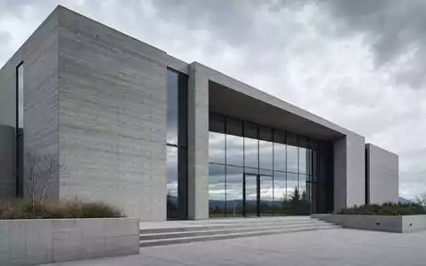Architekturfotografie eines modernen Gebäudes mit Sichtbeton-Fassade und Glaseingang – repräsentiert die Hochleistungsbetone der Heidelberg Materials AG (ISIN DE0006047004) in der Architektur - Foto: THN