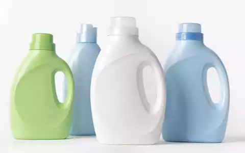 Fotorealistisch inszenierte generische Waschmittelflaschen aus Kunststoff in Blau, Grün und Weiß auf weißem Studio-Hintergrund – ein typisches Produktbild aus dem Segment Wasch- und Reinigungsmittel, wie es für die Henkel AG & Co. KGaA (ISIN DE0006048432) und ihr Konsumgütergeschäft steht - Foto: THN