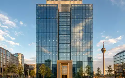 Professionelle Architekturfotografie eines modernen Glas-Stahl-Büroturms am Düsseldorfer Rheinufer mit dem Rheinturm im Hintergrund – verweist auf den Hauptsitz der Henkel AG & Co. KGaA (ISIN DE0006048432) in Düsseldorf, Deutschland - Foto: THN